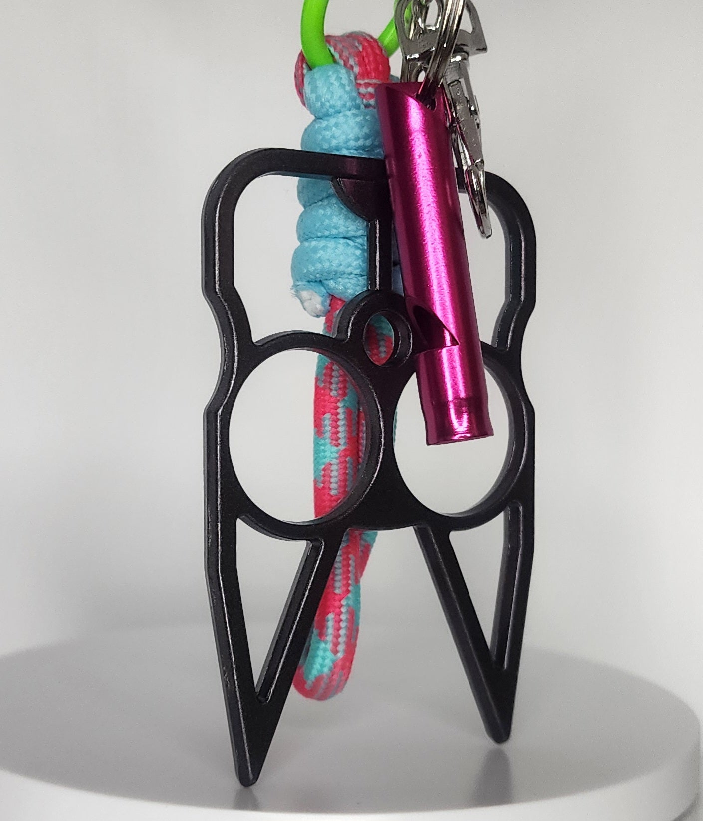 Black safety keychain with pink whistle and colorful rope on a white background