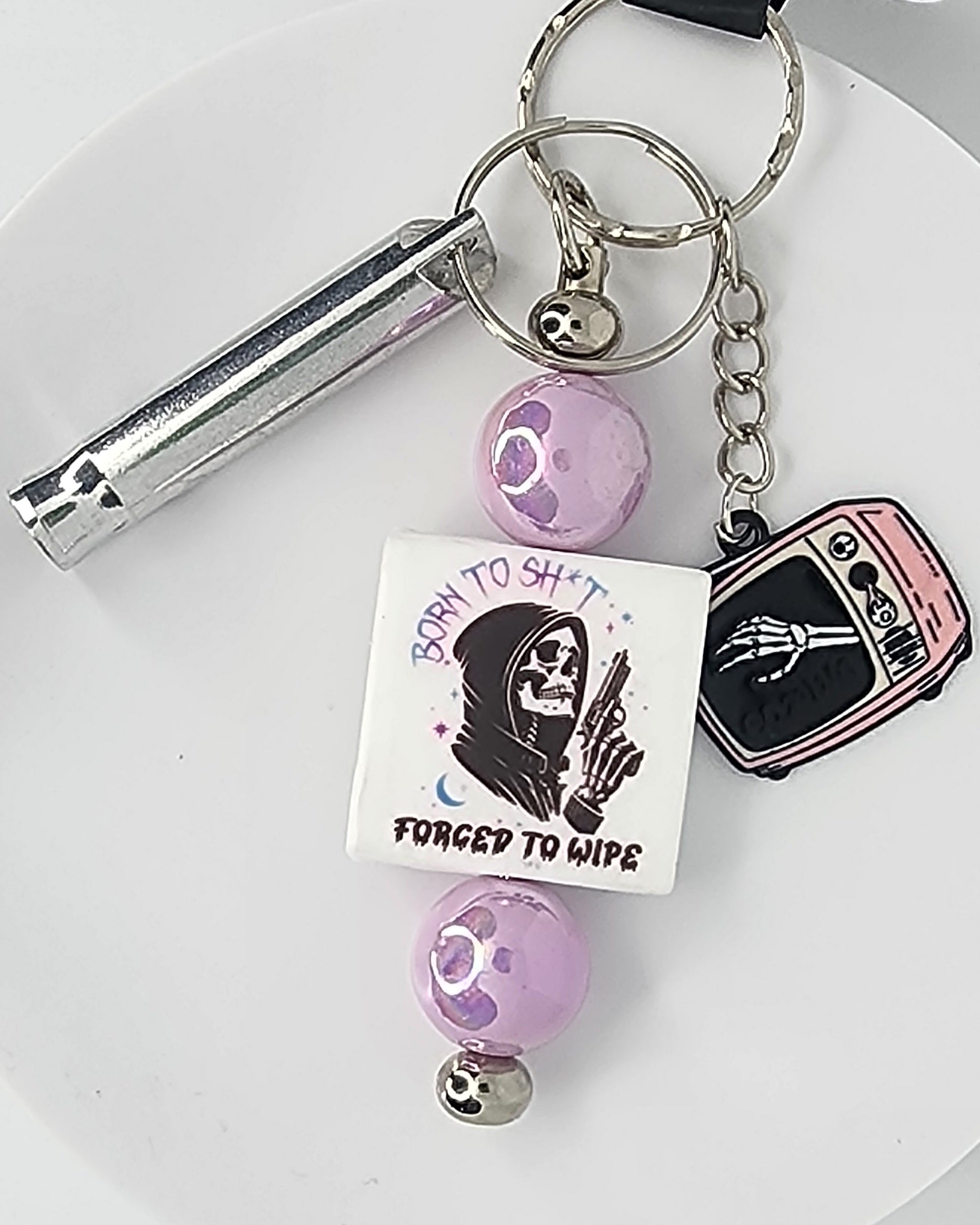 Keychain with various charms including a skeleton and text on a white background