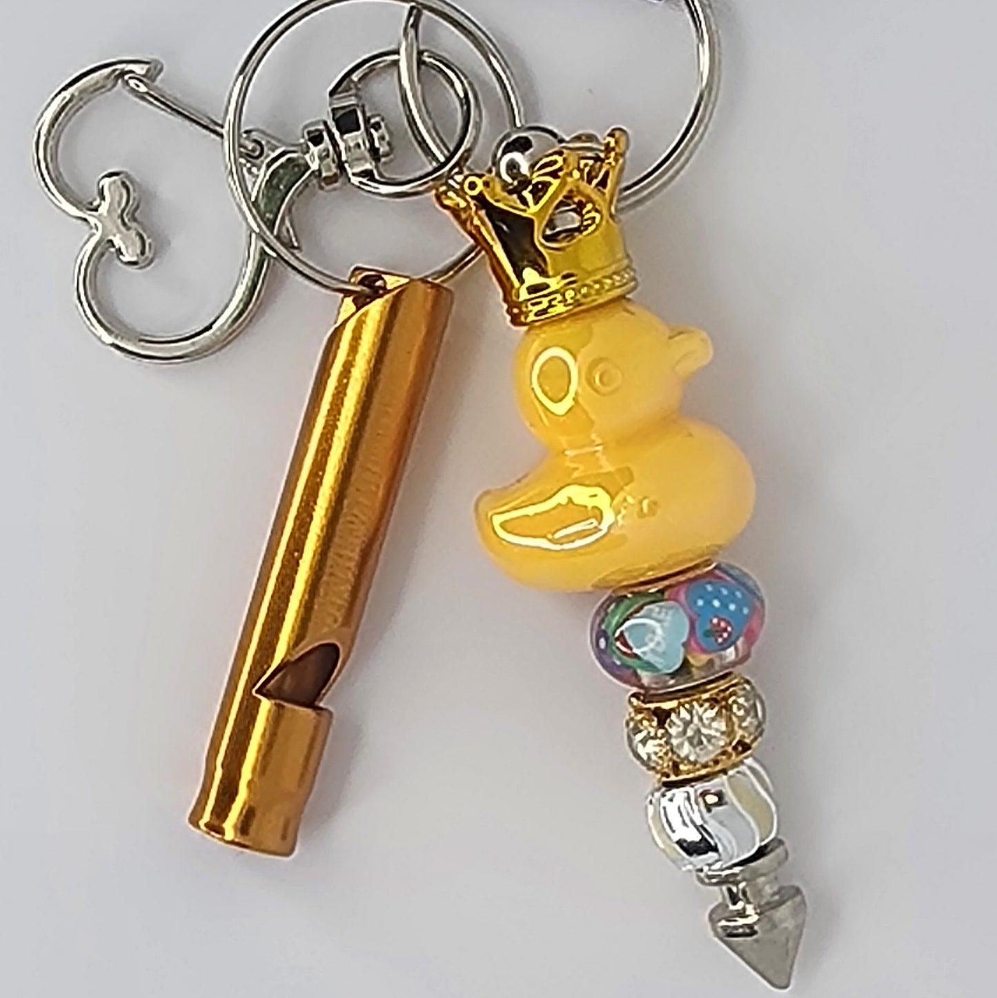 Keychain with gold whistle, yellow rubber duck, and colorful beads on a white background