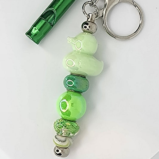Green beaded keychain with a metal whistle on a white background