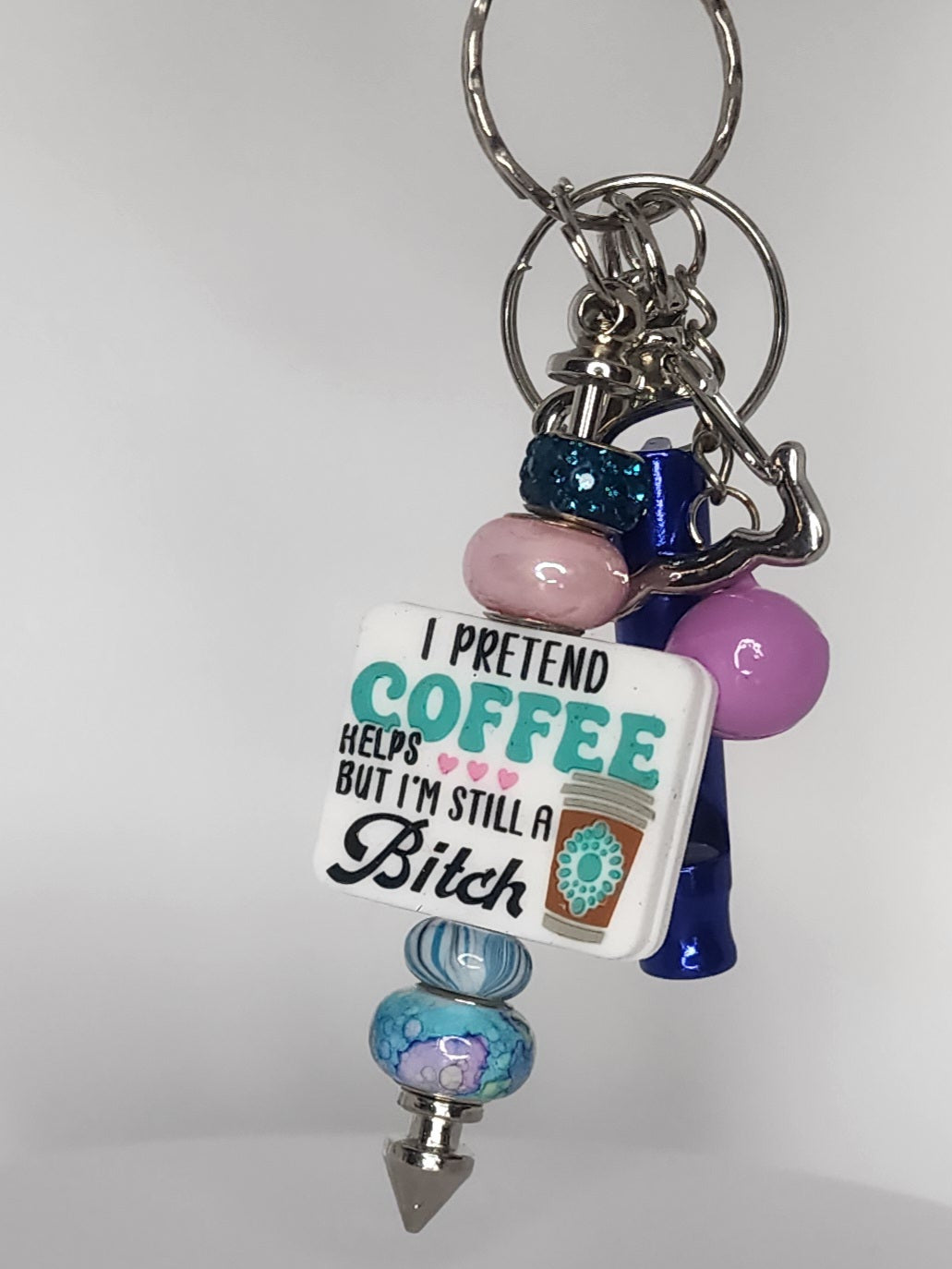 Keychain with colorful beads and a humorous tag on a white background