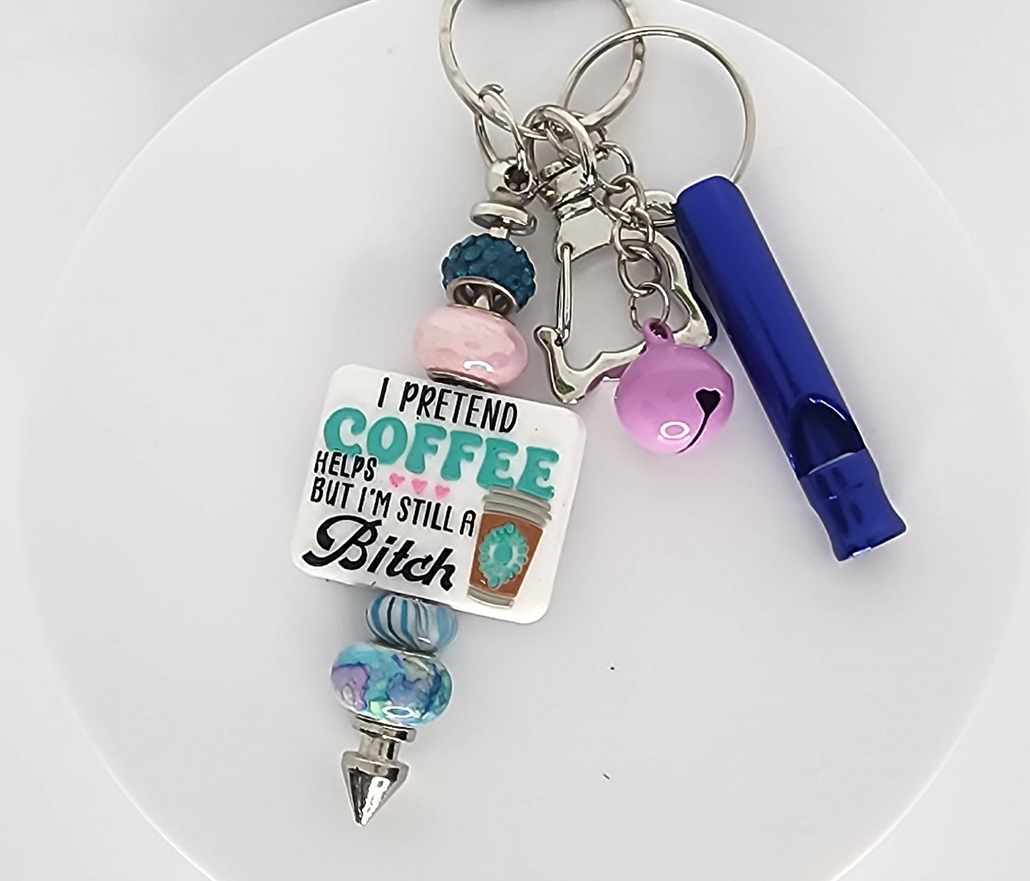 Keychain with colorful beads and a humorous tag on a white plate