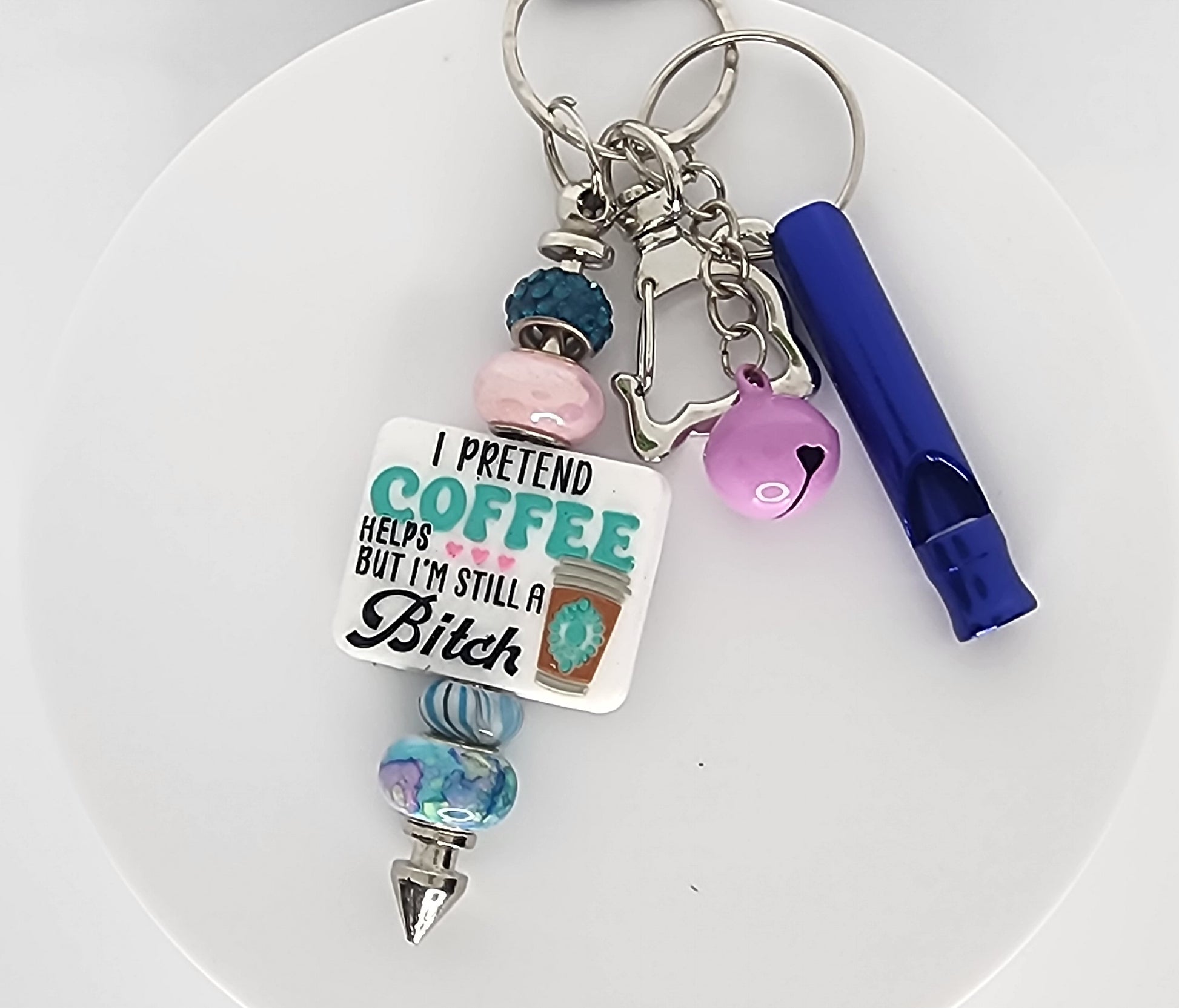 Keychain with colorful beads and a humorous tag on a white plate