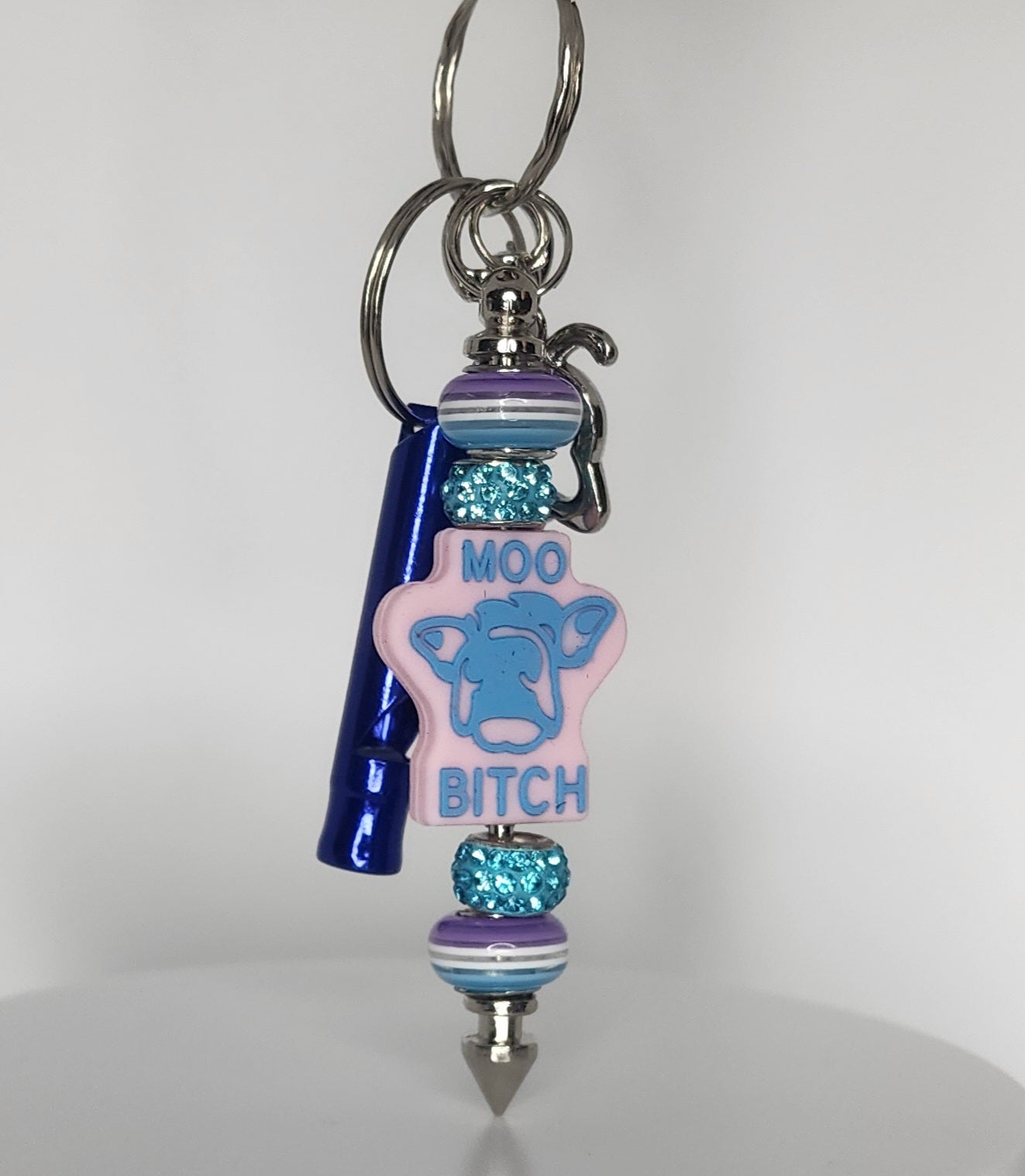 Keychain with blue cow figure and text 'MOO BITCH' on a white background